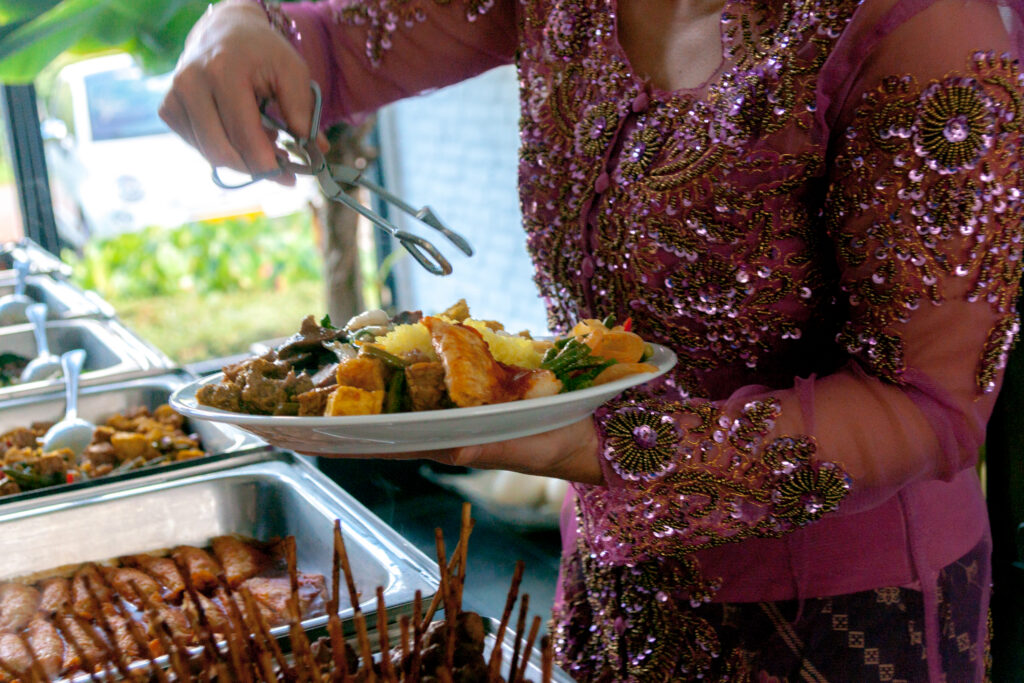 Gastvrouw serveert Indonesische gerechten bij een catering van Gembira
